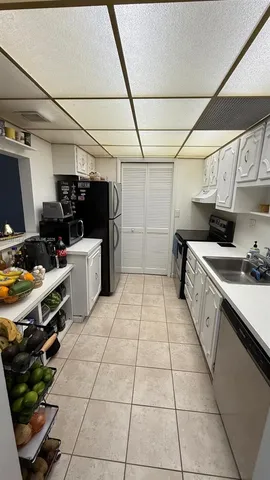 a large white kitchen with a stove a sink dishwasher and a refrigerator with wooden floor