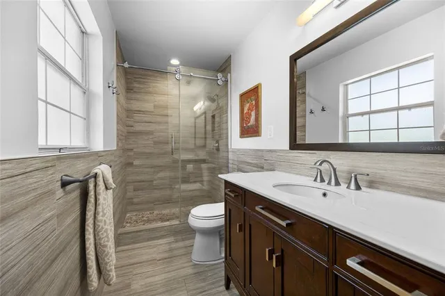 a bathroom with a sink a toilet a mirror and shower