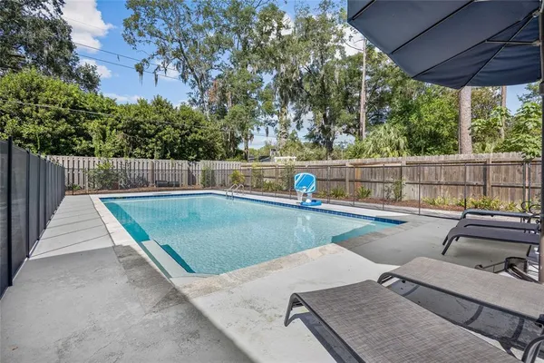 a view of a swimming pool with a patio and trees