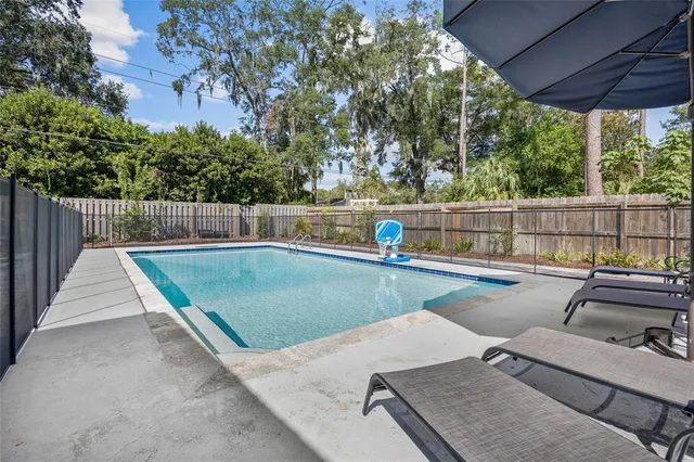 a view of a swimming pool with a patio and trees