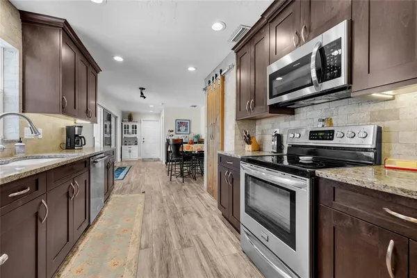a kitchen with stainless steel appliances granite countertop a stove a sink and a microwave