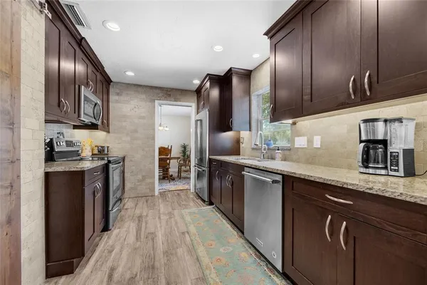 a kitchen with stainless steel appliances granite countertop refrigerator a sink and wooden cabinets