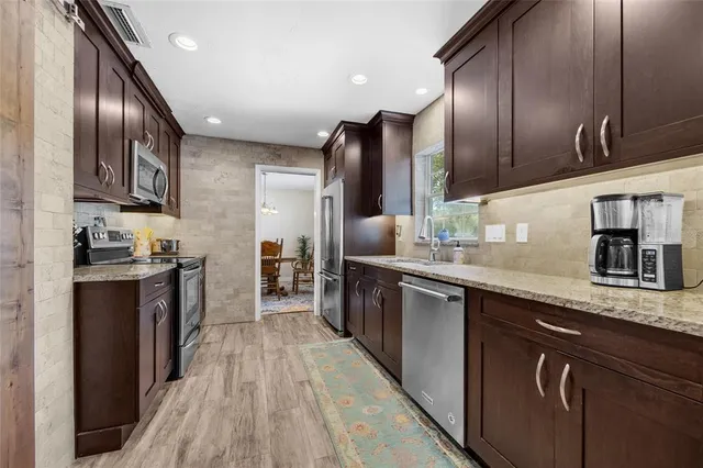 a kitchen with stainless steel appliances granite countertop refrigerator a sink and wooden cabinets