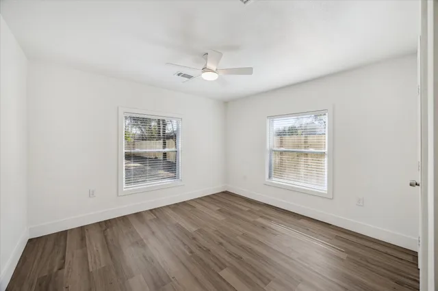 a view of an empty room with a window and wooden floor