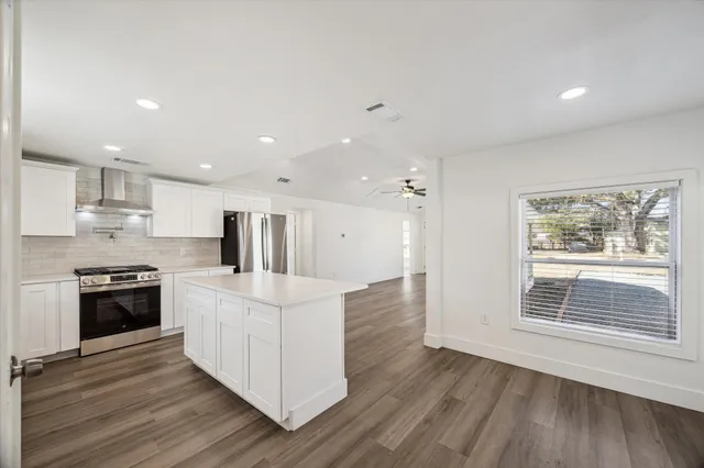 a large white kitchen with stainless steel appliances granite countertop a stove and a refrigerator