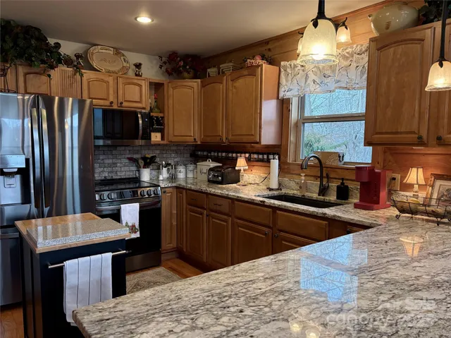 a kitchen with stainless steel appliances granite countertop a sink refrigerator stove and microwave