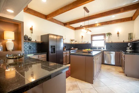 a kitchen with stainless steel appliances granite countertop a sink a stove and a refrigerator