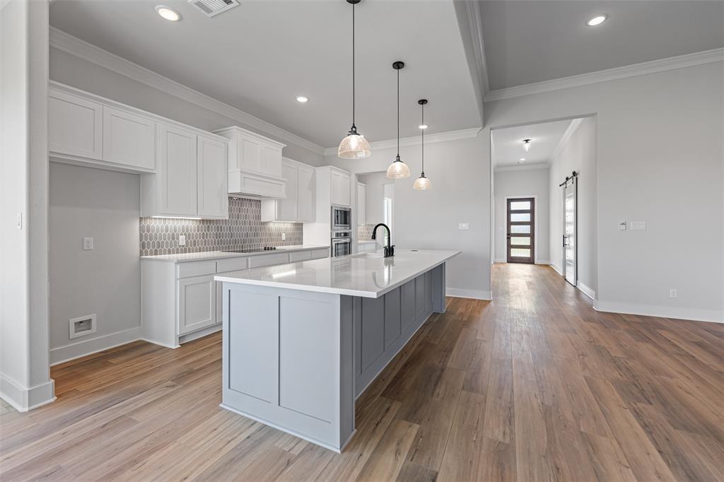 12108 Crystal Drive Krum, TX 76249 - Photo 26 of 40 a large white kitchen with a large kitchen island white cabinetry and wooden floor