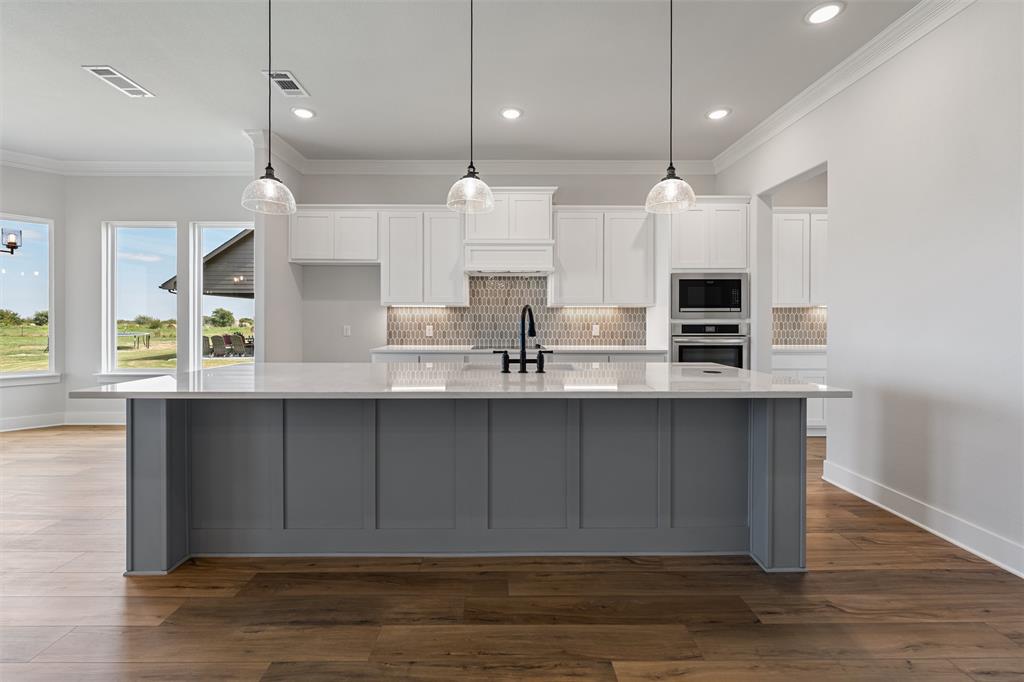 12108 Crystal Drive Krum, TX 76249 - Photo 27 of 40 a kitchen with kitchen island a sink and a stove top oven