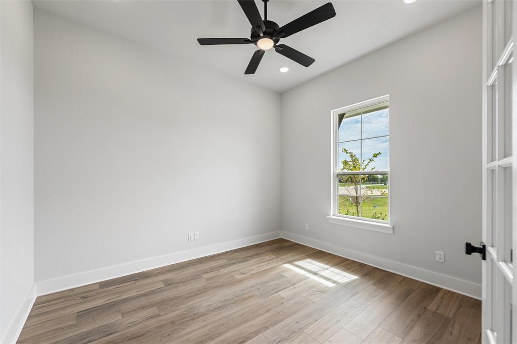 12108 Crystal Drive Krum, TX 76249 - Photo 10 of 40 an empty room with wooden floor ceiling fan and windows