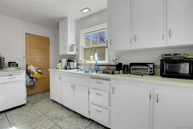 a kitchen with white cabinets and sink