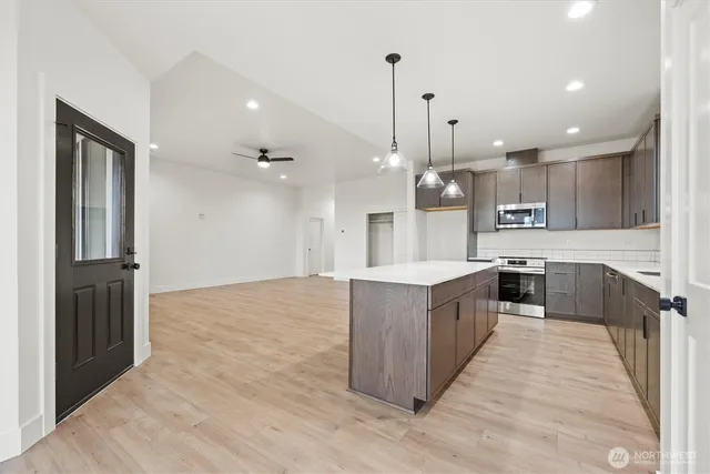 a large kitchen with granite countertop a large counter top a sink stainless steel appliances and cabinets