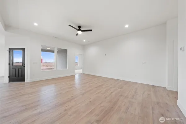 a view of an empty room with wooden floor and a ceiling fan