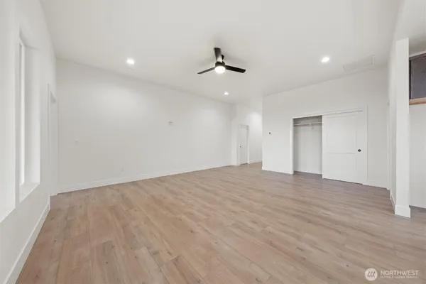 an empty room with wooden floor ceiling fan and windows