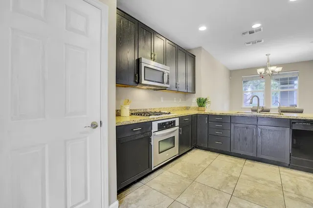 a kitchen with stainless steel appliances granite countertop a stove a sink and a refrigerator