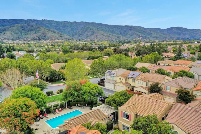 a sign board with flower plants and large trees