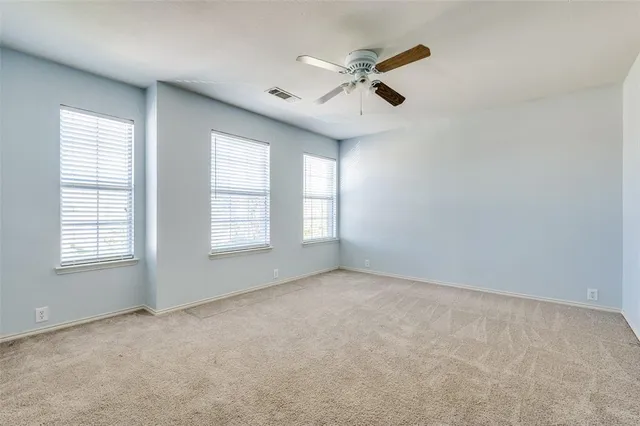 an empty room with windows and fan