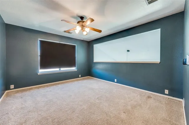 a view of an empty room with a ceiling fan and a window