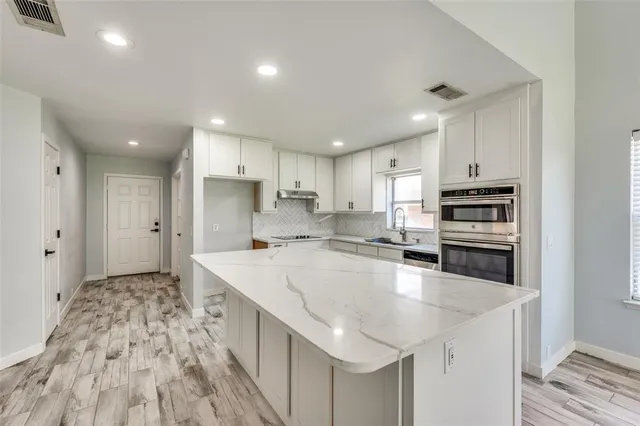 a large kitchen with stainless steel appliances a large counter top a stove and a refrigerator