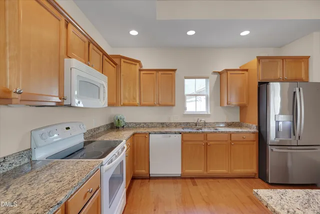 a kitchen with granite countertop a sink a counter space appliances and cabinets