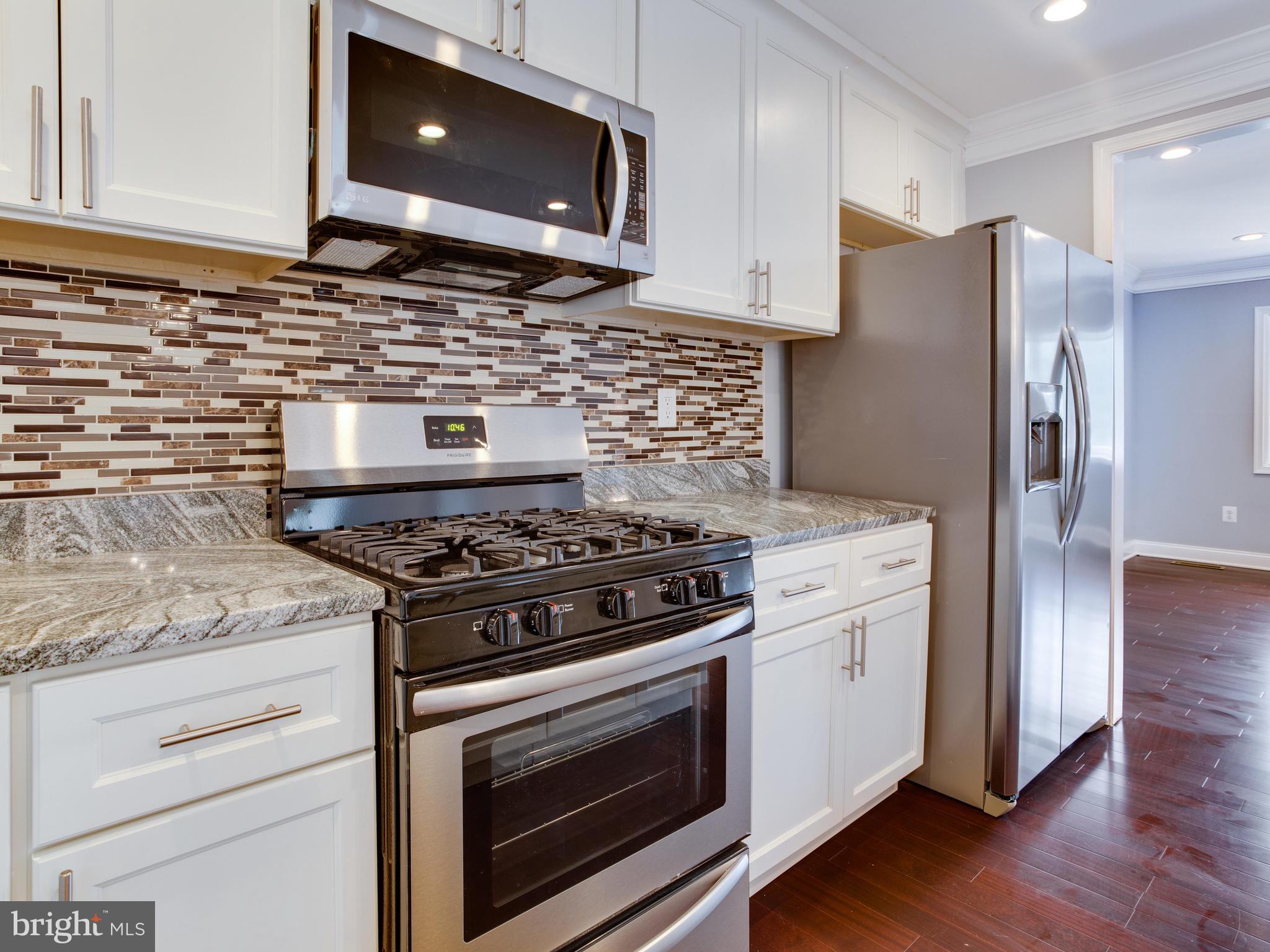 6006 Queens Chapel Road Hyattsville, MD 20782 - Photo 6 of 19 a kitchen with stainless steel appliances granite countertop a stove a microwave and a refrigerator
