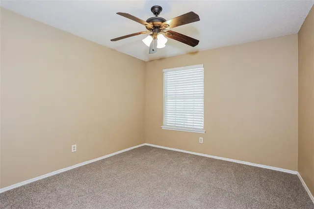 an empty room with a chandelier fan and windows