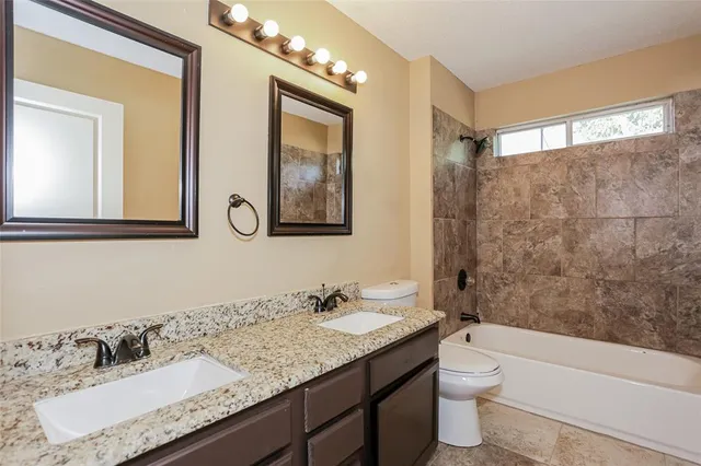 a bathroom with a granite countertop sink a toilet a mirror and shower