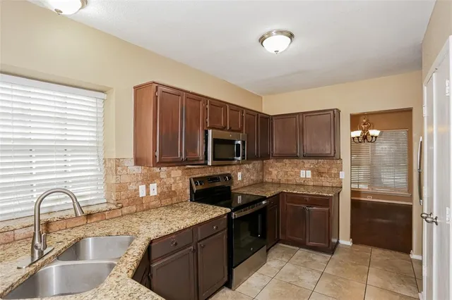 a kitchen with granite countertop a stove sink and refrigerator