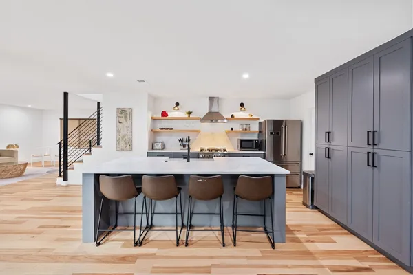 a dining hall with stainless steel appliances kitchen island granite countertop a dining table and chairs with wooden floor