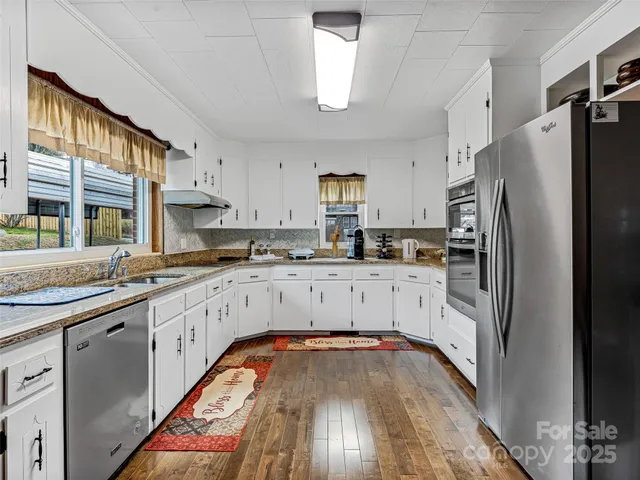 a kitchen with granite countertop a refrigerator and white cabinets