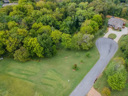 an aerial view of residential house with outdoor space and trees all around