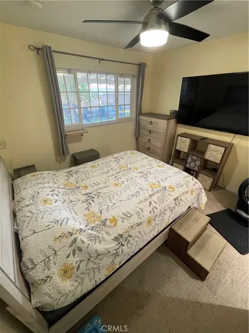 a bedroom with a bed and a television on the dresser