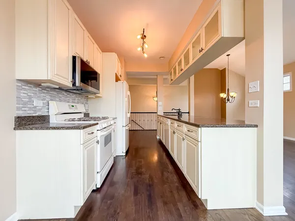a kitchen with white cabinets and wooden floors