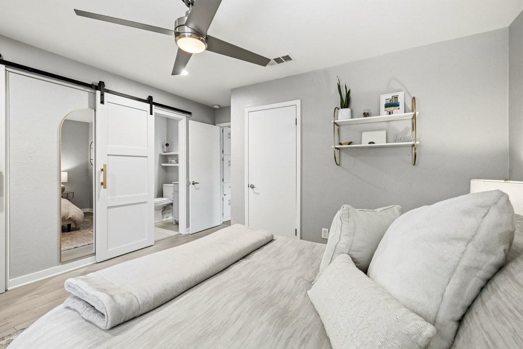 658 Mairo Street Austin, TX 78748 - Photo 25 of 40 Elegant barn doors lead to a well-appointed primary bathroom, complementing the bedroom's clean aesthetic.