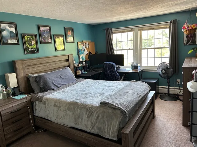a bedroom with a bed a couch and a dresser next to a window