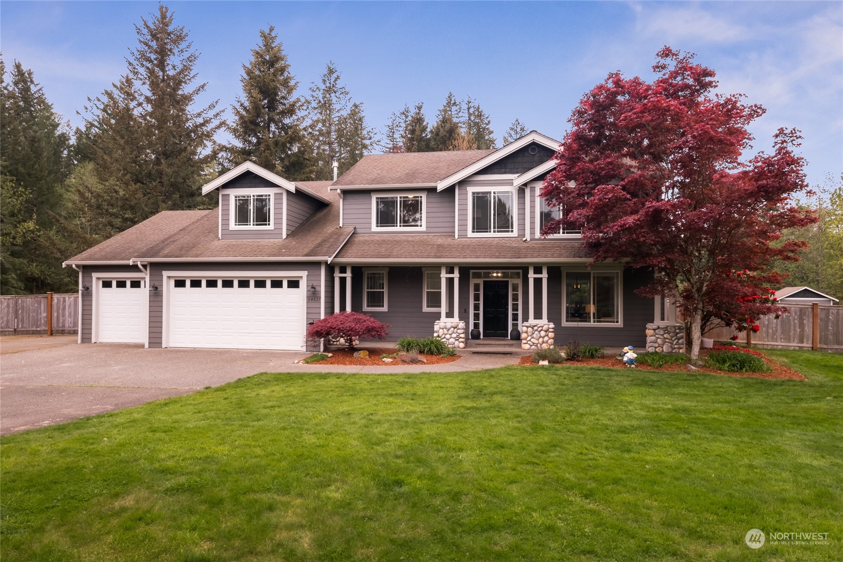 a front view of a house with a garden and trees