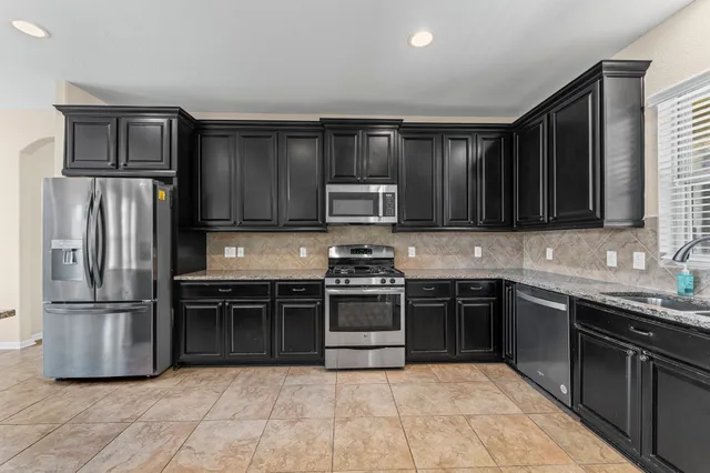 a kitchen with stainless steel appliances granite countertop a stove top oven a sink and a refrigerator