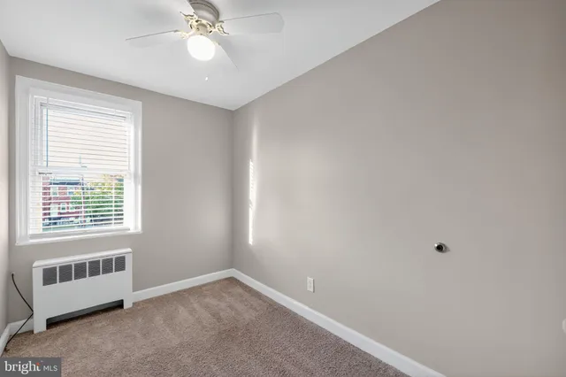 an empty room with a window and a ceiling fan
