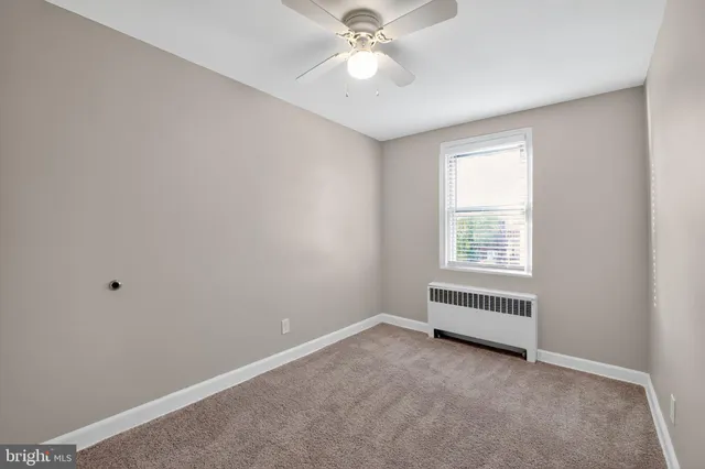 an empty room with a window and a fan