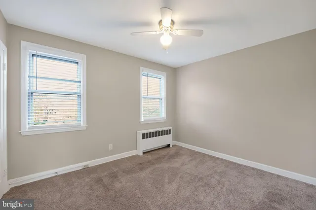 an empty room with windows and ceiling fan