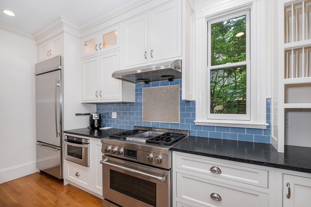 a kitchen with stainless steel appliances white cabinets and a stove top oven