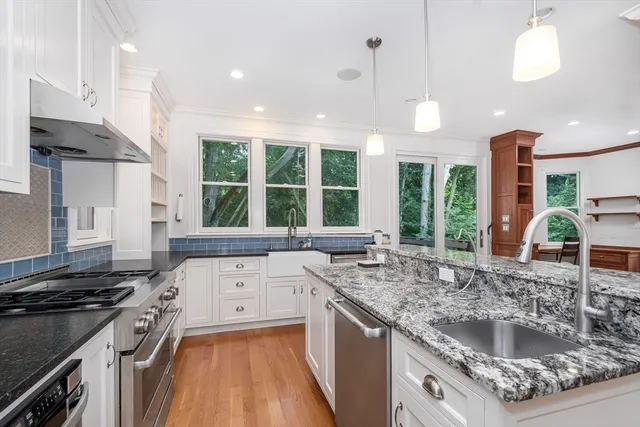 a kitchen with stainless steel appliances granite countertop a sink a stove and a wooden floors