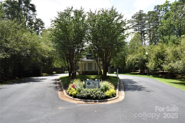 a view of a white house with a big yard plants and large trees
