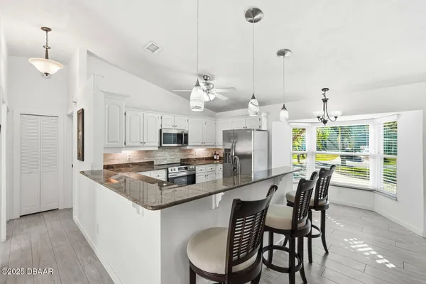 a kitchen with stainless steel appliances granite countertop a kitchen island a stove a table and chairs