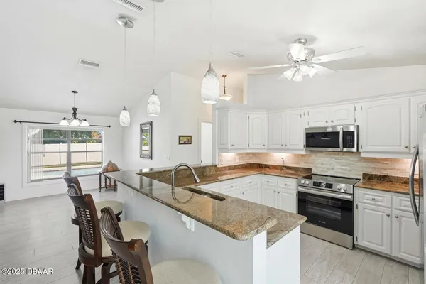 a kitchen with a stove a sink and chairs