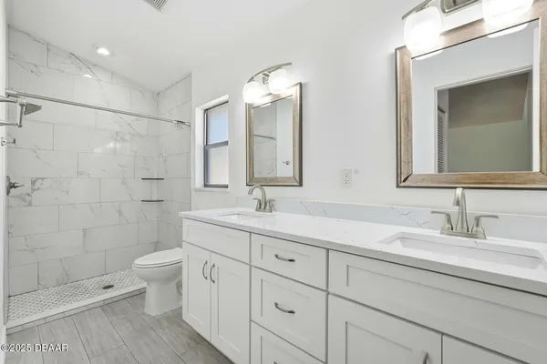 a bathroom with a double vanity sink mirror and toilet
