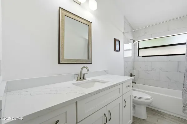 a bathroom with a granite countertop sink a toilet and a bathtub
