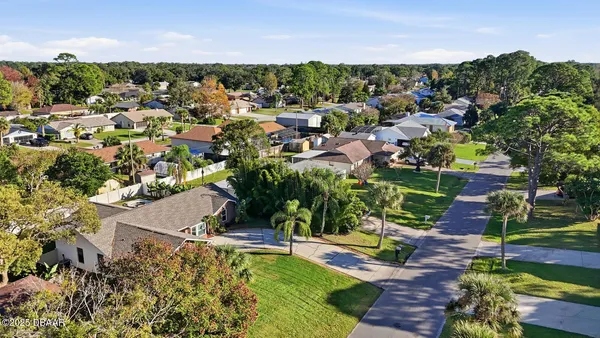 an aerial view of residential houses with outdoor space and trees