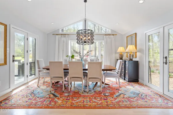 a dining room with chandelier and wooden floor