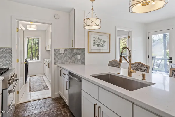 a kitchen with stainless steel appliances granite countertop a sink dishwasher stove and white countertops with wooden floor